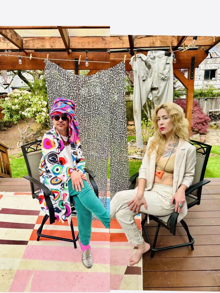 Two people in colorful, stylish costumes sit in front of a leopard print background on a backyard deck